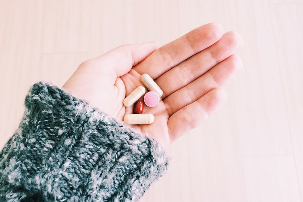 A hand holding a selection of pills